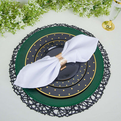 Elegant black and green dinner plate set with white napkin and decorative holder.