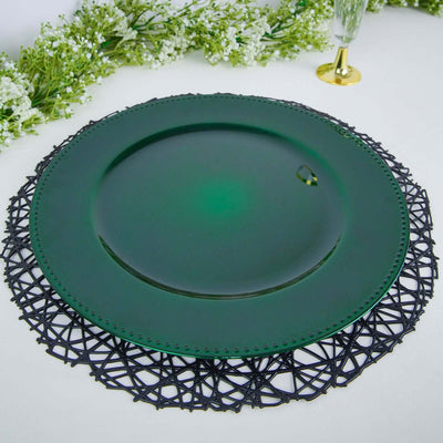 Green glass plate on an intricate black lace charger surrounded by floral decor.