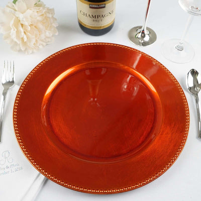 Elegant orange charger plate with gold rim on a dining table setting.
