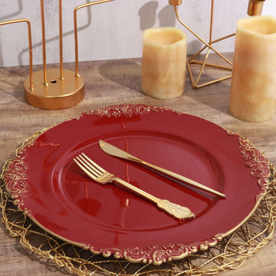 Elegant red plate with gold cutlery and decorative elements on a rustic table.