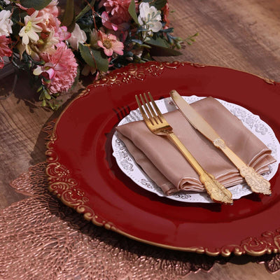 Elegant red plate set with gold cutlery and a folded napkin, adorned with flowers.