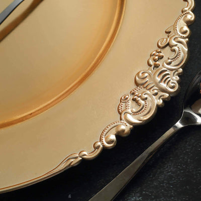 Elegant gold dinner plate with ornate rim design and silver spoon.
