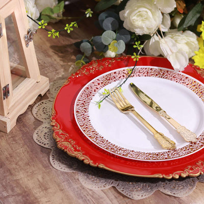 Elegant red and white dinner plate set with gold utensils on a rustic table.