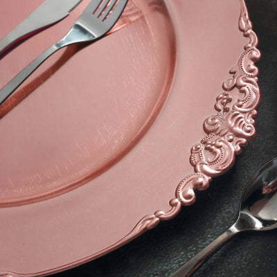 Pink ornate charger plate with silver forks and spoons.
