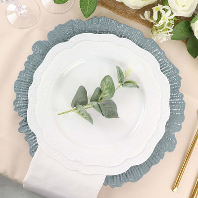 Elegant white plate with green leaves on layered decorative chargers.