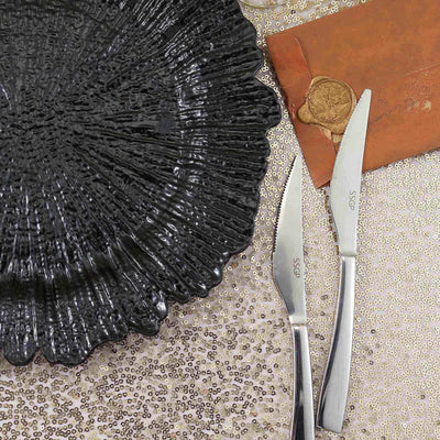 Elegant black plate with two stainless steel knives on a sparkling background.