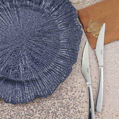 Elegant blue textured plate with silver cutlery on a sparkling surface.