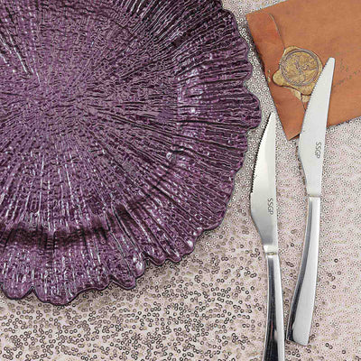 Purple textured plate with stainless steel knives on a sequined surface.