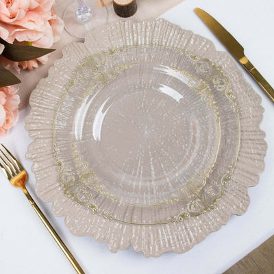 Elegant clear glass plate with decorative gold rim on a textured surface.