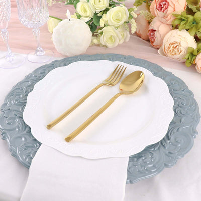 Elegant table setting with white and gray plates, gold cutlery, and floral accents.