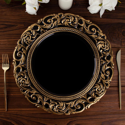 Ornate gold charger plate on a wooden table with silver utensils.