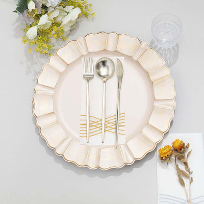 Elegant gold-rimmed plate with cutlery and decorative napkin on a table.