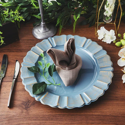 Elegant blue plate with a folded napkin and greenery on a wooden table.