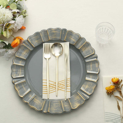 Elegant gray plate with gold trim, cutlery, and decorative napkin on a table.