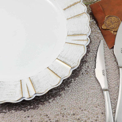 Elegant white plate with gold rim on a sequined tablecloth.