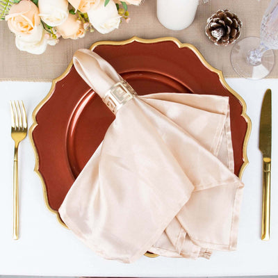 Elegant table setting with a copper plate, gold cutlery, and beige napkin.