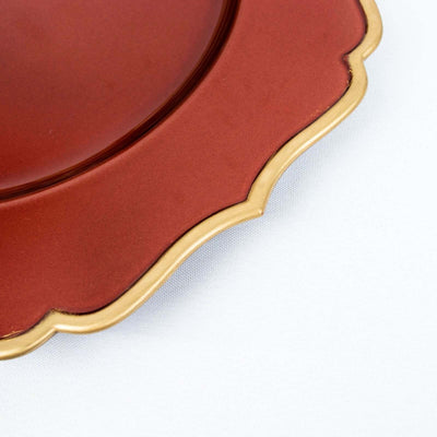 Red scalloped plate with gold trim on a white background.