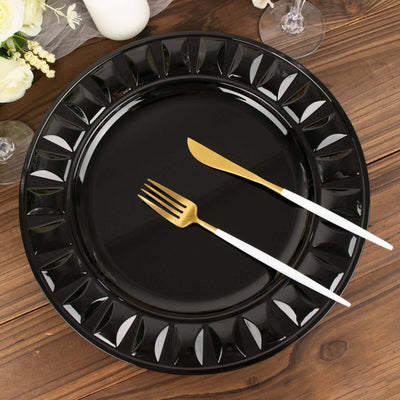 Elegant black dinner plate with gold cutlery on a wooden table setting.