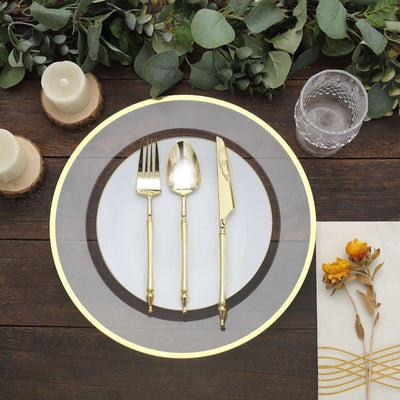 Elegant gold cutlery set on a decorative plate with greenery and candles
