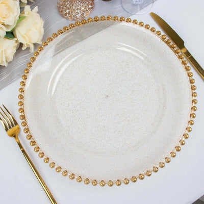 Elegant gold-beaded clear glass charger plate on a table setting.