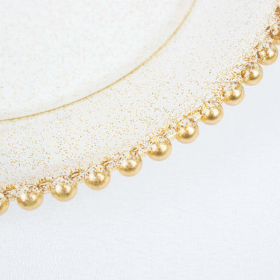 Elegant glass plate with gold bead trim on a white background.