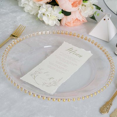 Elegant clear glass plate with gold bead rim and floral menu card on a table setting.