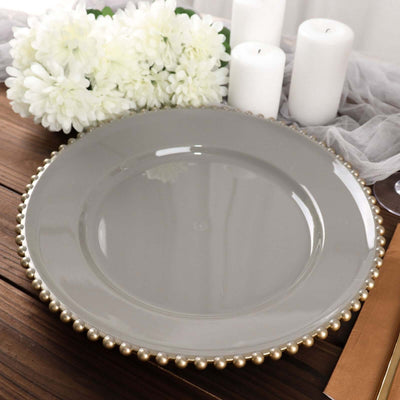 Gray plate with pearl trim on a wooden table with white flowers and candles.