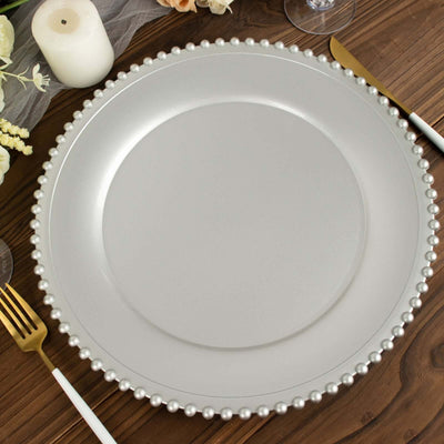Silver charger plate with pearl trim on wooden table setting.