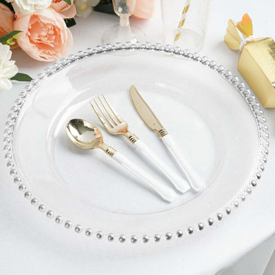 Clear plate with gold-accented cutlery on a table setting.