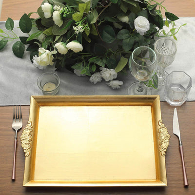 Elegant gold serving tray on a table with floral arrangement and glassware.