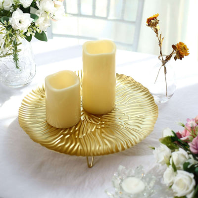 Gold decorative plate with two candles surrounded by flowers.