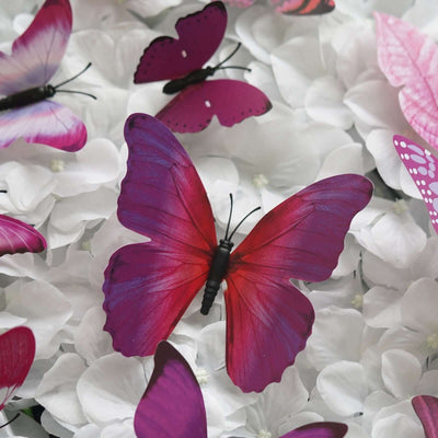 Colorful artificial butterflies on a bed of white flowers.