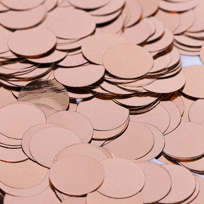 Rose gold confetti circles scattered on a surface.