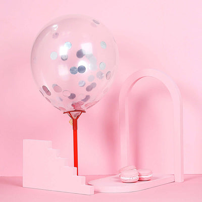 Pink balloon with confetti and macarons on a pastel pink backdrop.
