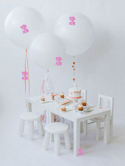 Children's party setup with balloons and treats on a white table.