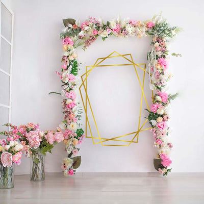 Floral arch with pink flowers and geometric gold design on a white wall.
