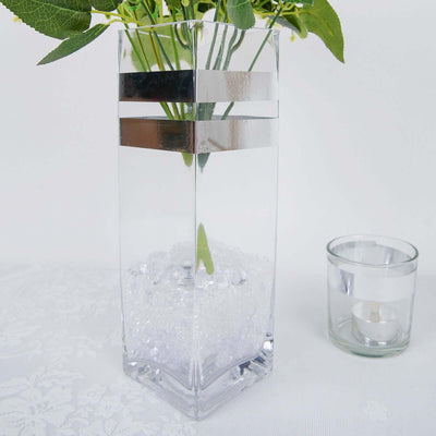Clear glass vase with silver accents and decorative filler stones.