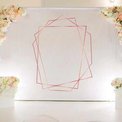 Geometric rose gold wedding backdrop with floral arrangements.