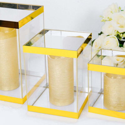 Gold candle holders in clear glass with yellow accents, set against a floral backdrop.