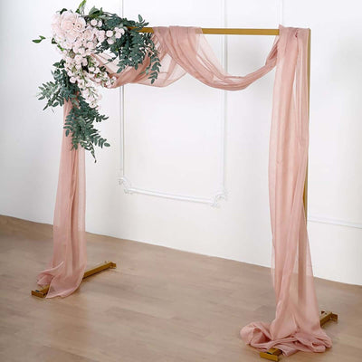 Floral arch with draped fabric in soft pink tones.