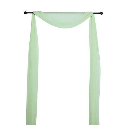 Sheer mint green fabric draped on a black curtain rod