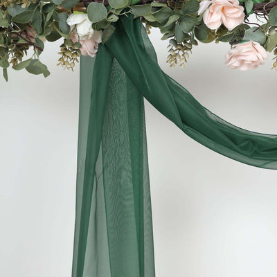 Green sheer fabric draped with floral accents against a white background.