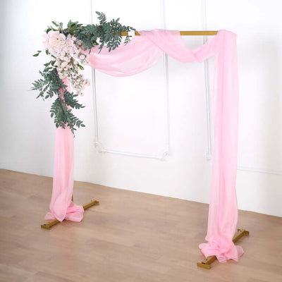 Pink wedding arch with floral accents and flowing drapes