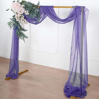 Purple draped fabric arch with floral accents for events and decorations.