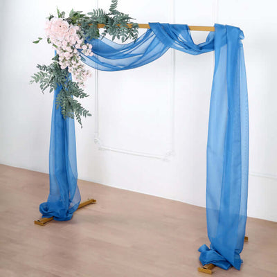 Blue sheer fabric wedding arch with floral accents.