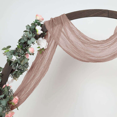 Boho wedding arch draped with soft fabric and floral accents