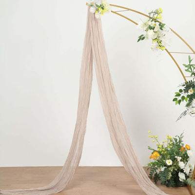 Soft beige drapery fabric hanging elegantly with floral arch backdrop.