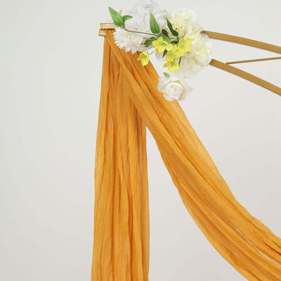 Orange fabric draped with floral accents on a gold frame