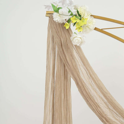 Beige textured fabric draped with white and yellow flowers on a gold frame.