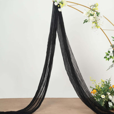 Black sheer fabric draped elegantly with floral arrangement in the background.